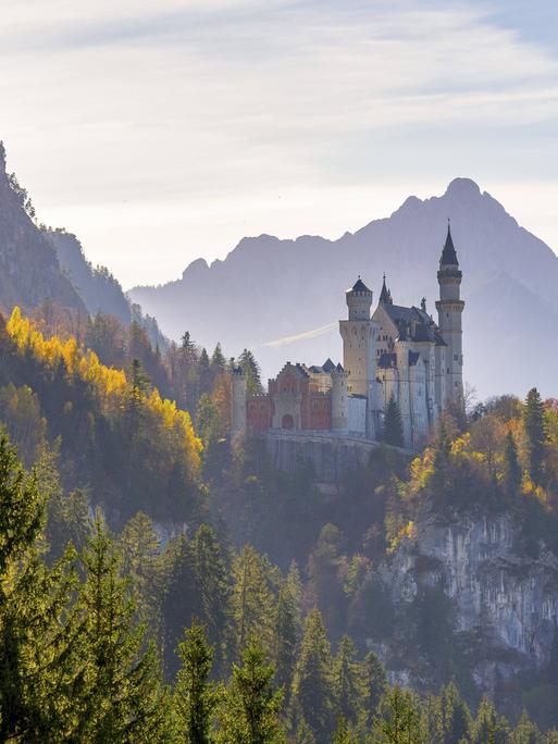 Schloss Neuschwanstein umgeben von buntem Herbstlaub und majestätischen Alpen