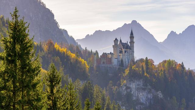 Schloss Neuschwanstein umgeben von buntem Herbstlaub und majestätischen Alpen