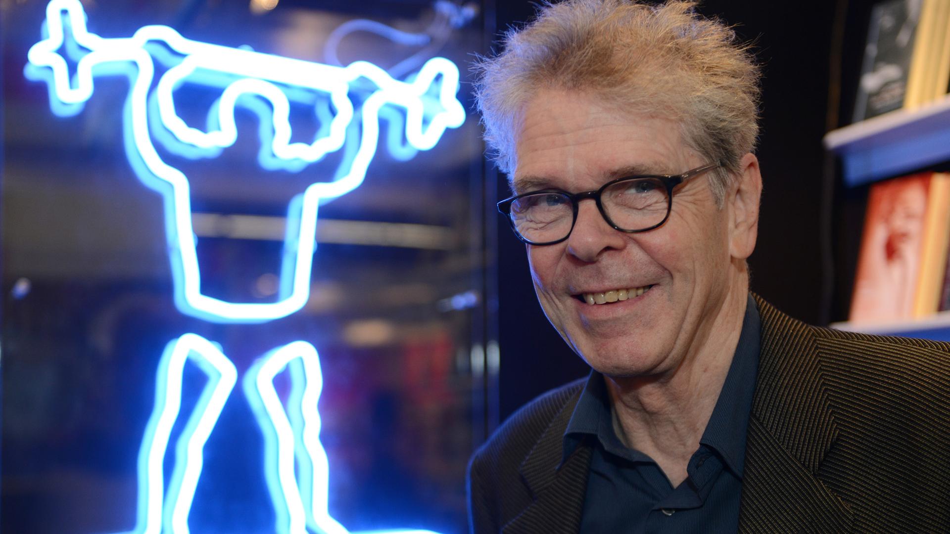 Heinrich von Berenberg neben einer Leuchtreklame auf der Frankfurter Buchmesse