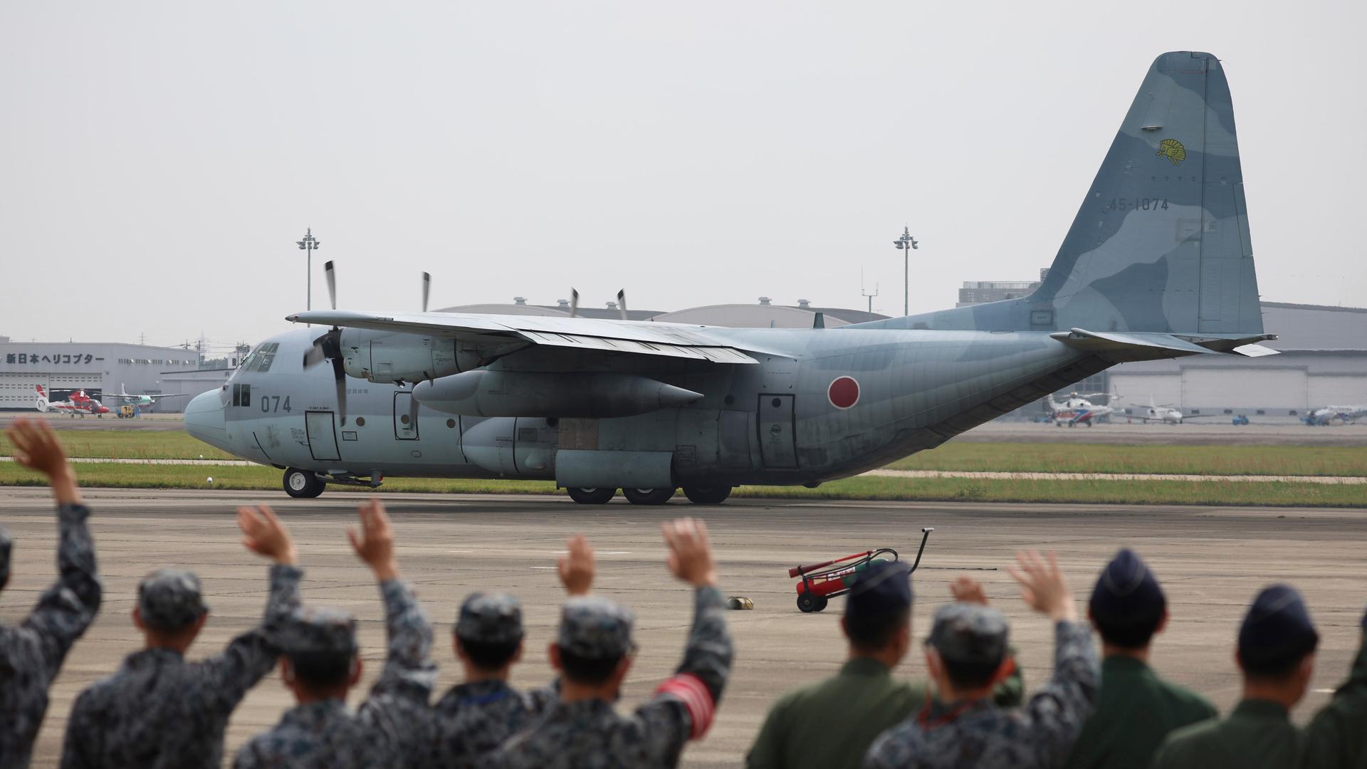 Mitglieder der japanischen Streitkräfte verabschieden ein Transportflugzeug, das Landsleute aus dem Sudan ausfliegen soll