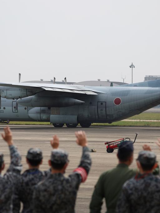 Mitglieder der japanischen Streitkräfte verabschieden ein Transportflugzeug, das Landsleute aus dem Sudan ausfliegen soll