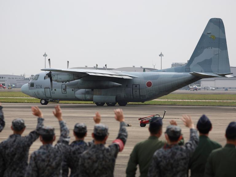 Mitglieder der japanischen Streitkräfte verabschieden ein Transportflugzeug, das Landsleute aus dem Sudan ausfliegen soll