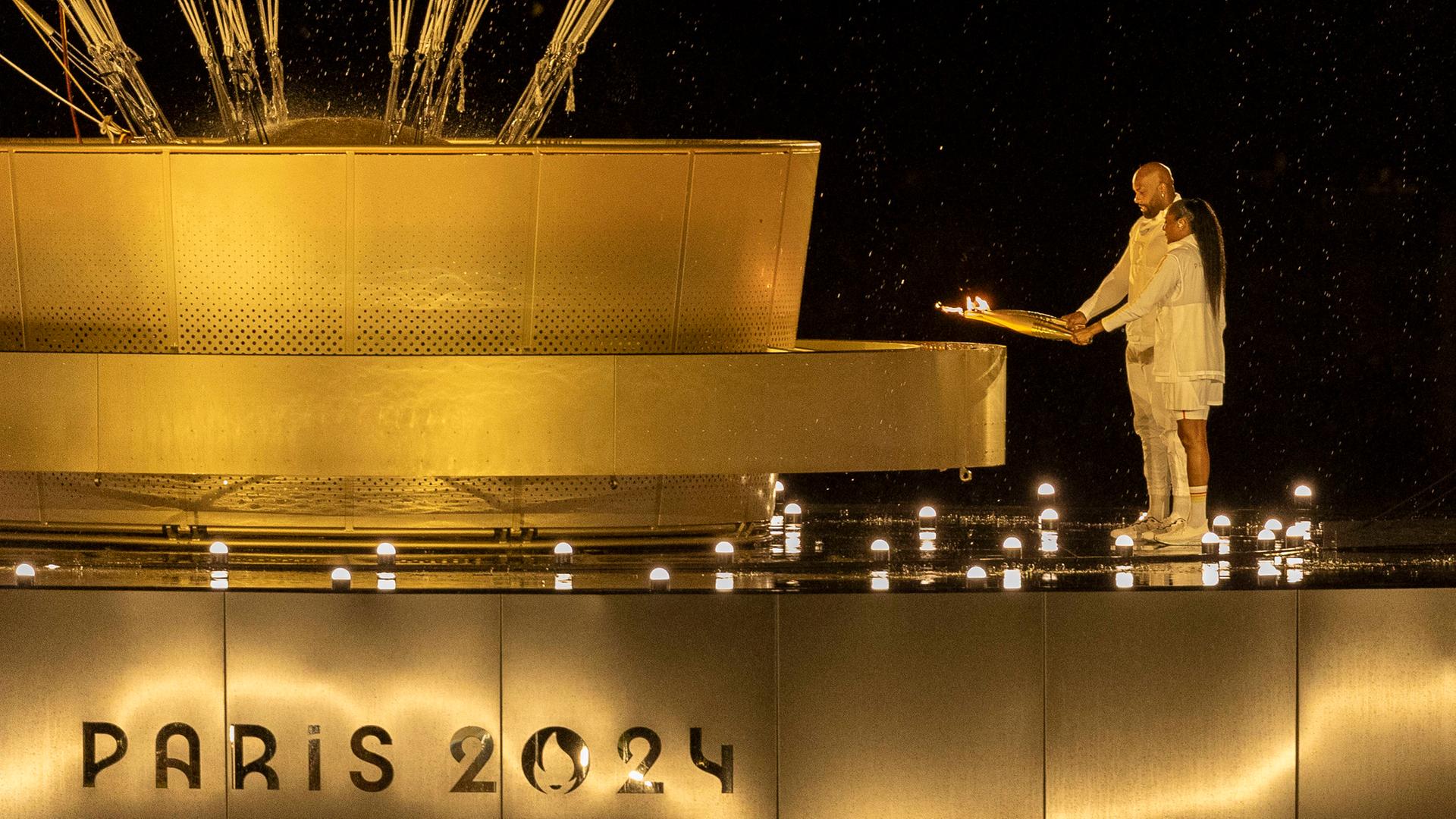 Marie-José Perec und Teddy Riner entzünden bei der Eröffnungsfeier der Olympischen Spiele in Paris das Olympische Feuer. 