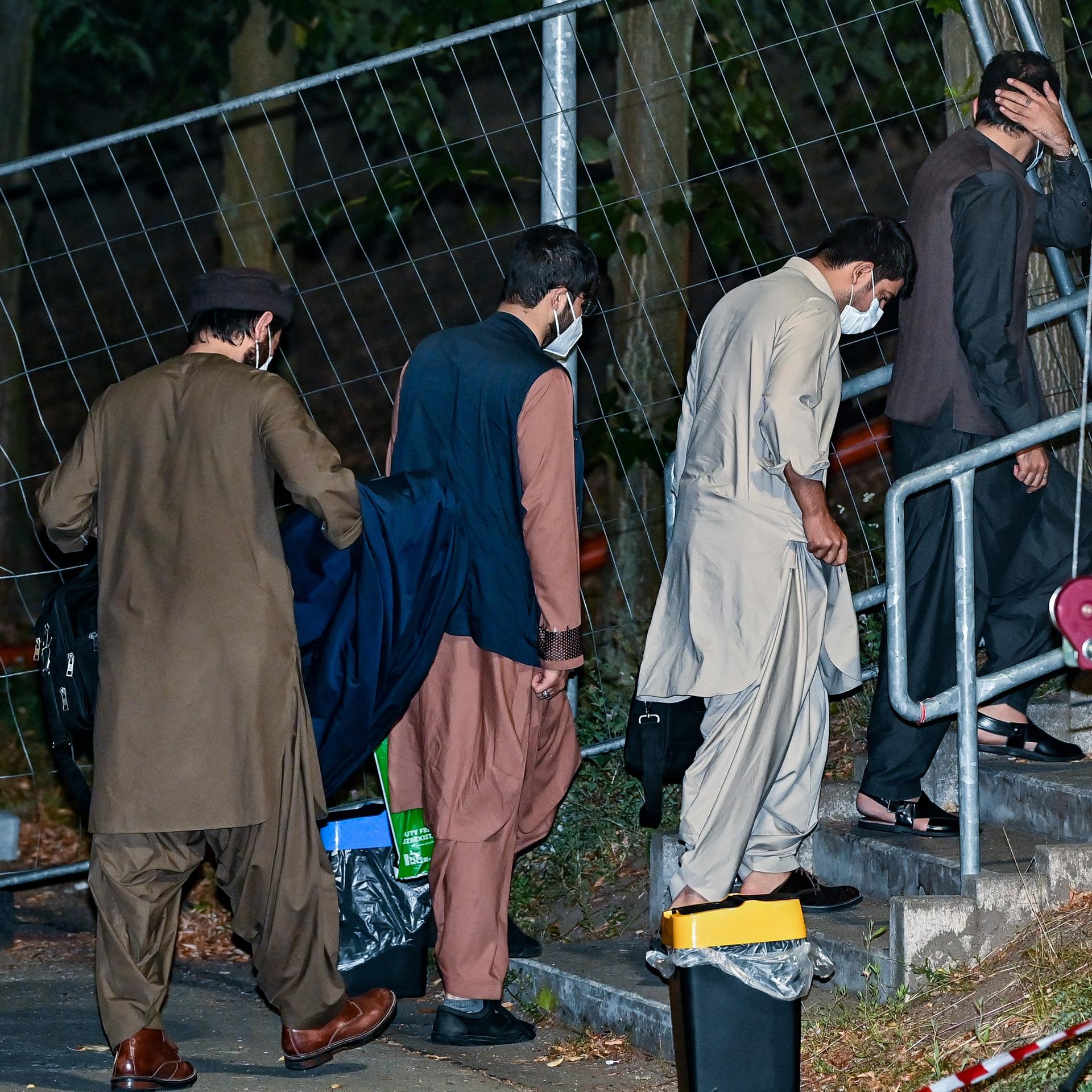 Ortskräfte aus Afghanistan gehen am frühen Morgen auf dem Gelände der DRK-Flüchtlingshilfe in der Erstaufnahmeeinrichtung zu ihrer Unterkunft. Gegen 4:30 Uhr am frühen Morgen sind zwei Busse vom Flughafen in Frankfurt am Main mit knapp 60 Ortskräften aus Afghanistan hier an der Zentralen Ausländerbehörde Brandenburgs angekommen.