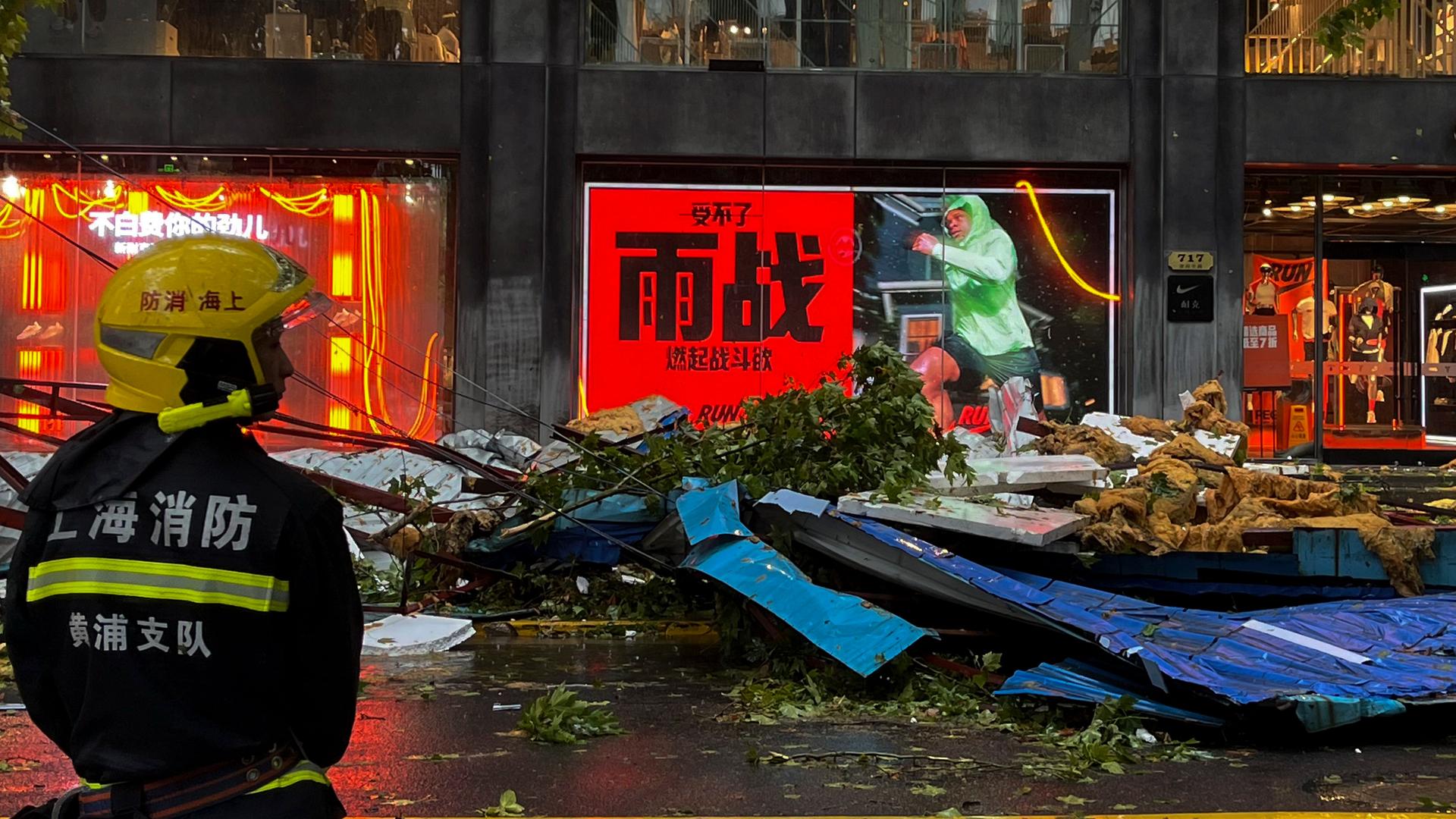 China, Shanghai: Ein Feuerwehrmann steht in der Nähe von Trümmern in einer Geschäftsstraße nach dem Taifun Bebinca.