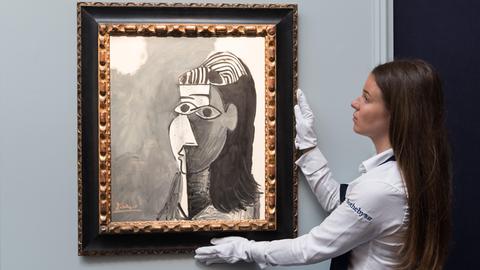 Eine Frau hält während einer Präsentation des Auktionshauses Sotheby's das Bild "Tete de femme" von Pablo Picasso
