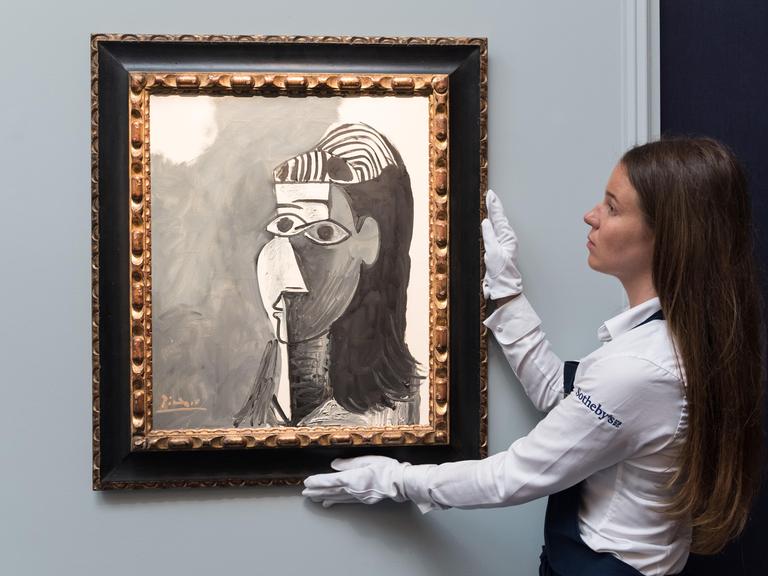 Eine Frau hält während einer Präsentation des Auktionshauses Sotheby's das Bild "Tete de femme" von Pablo Picasso