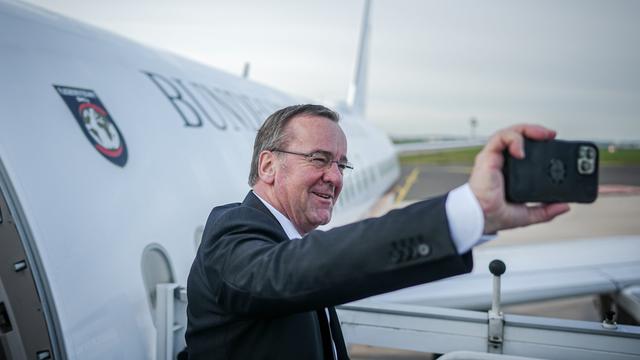 Bundesverteidigungsminister Boris Pistorius fotografiert sich mit seinem Handy selbst auf dem militärischen Teil des Flughafens BER Berlin-Brandenburg vor dem Airbus der Flugbereitschaft.