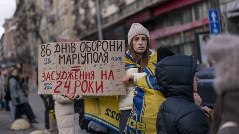 Eine Frau hält ein Pappschild in die Luft, welcher an die Verteidiger des Azowstal-Werks erinnert. Die Männer befinden sich seit fast zwei Jahren in der Gefangenschaft russischer Streitkräfte. 