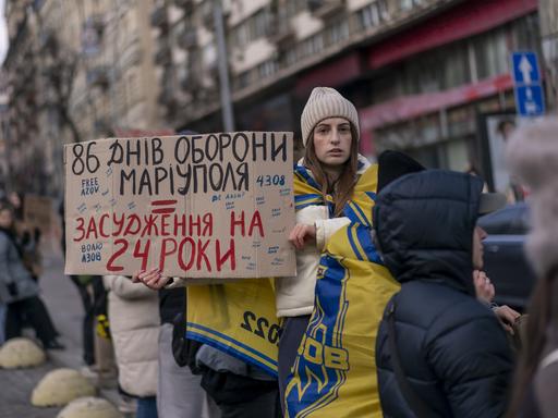 Eine Frau hält ein Pappschild in die Luft, welcher an die Verteidiger des Azowstal-Werks erinnert. Die Männer befinden sich seit fast zwei Jahren in der Gefangenschaft russischer Streitkräfte. 