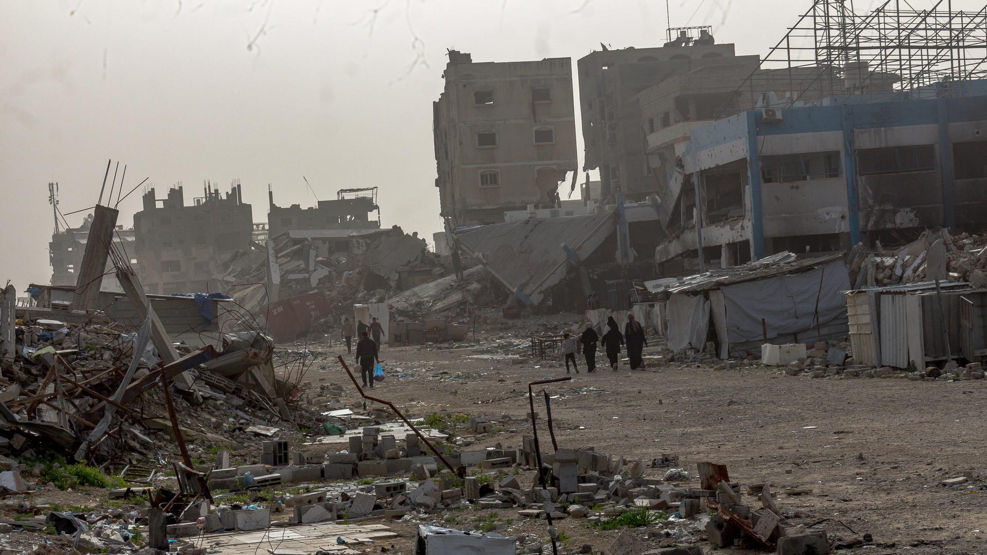 Palästinenser laufen durch eine zerstörte Umgebung. 