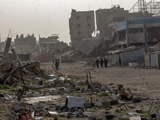 Palästinenser laufen durch eine zerstörte Umgebung. 