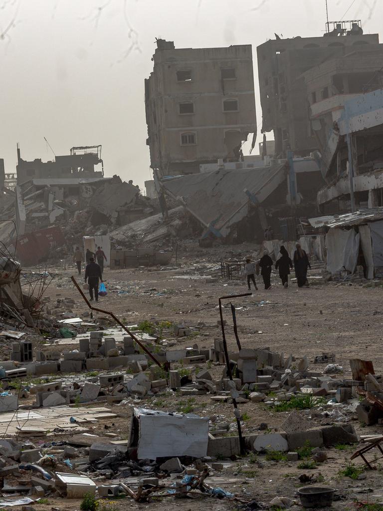 Palästinenser laufen durch eine zerstörte Umgebung. 