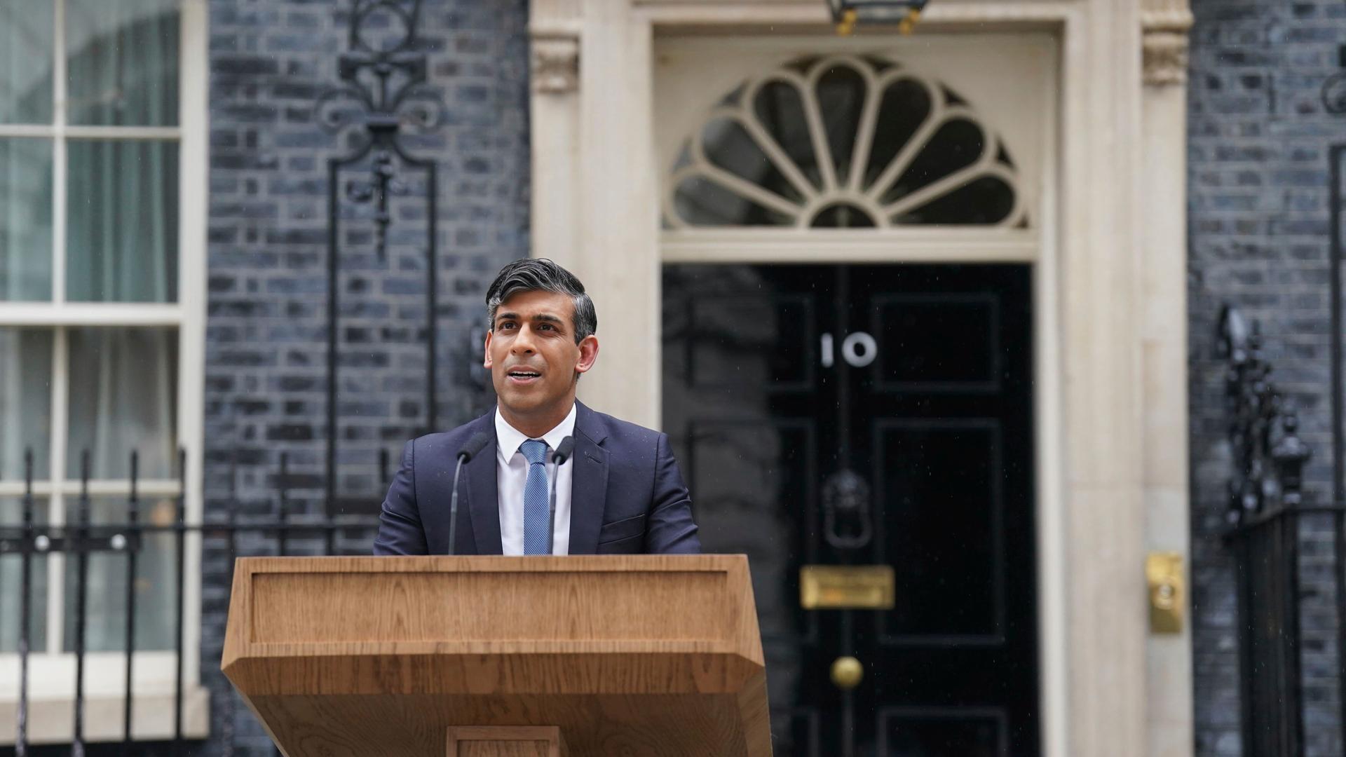 Der britische Premierminister Rishi Sunak steht vor der Downing Street Nr. 10 hinter einem Rednerpult.
