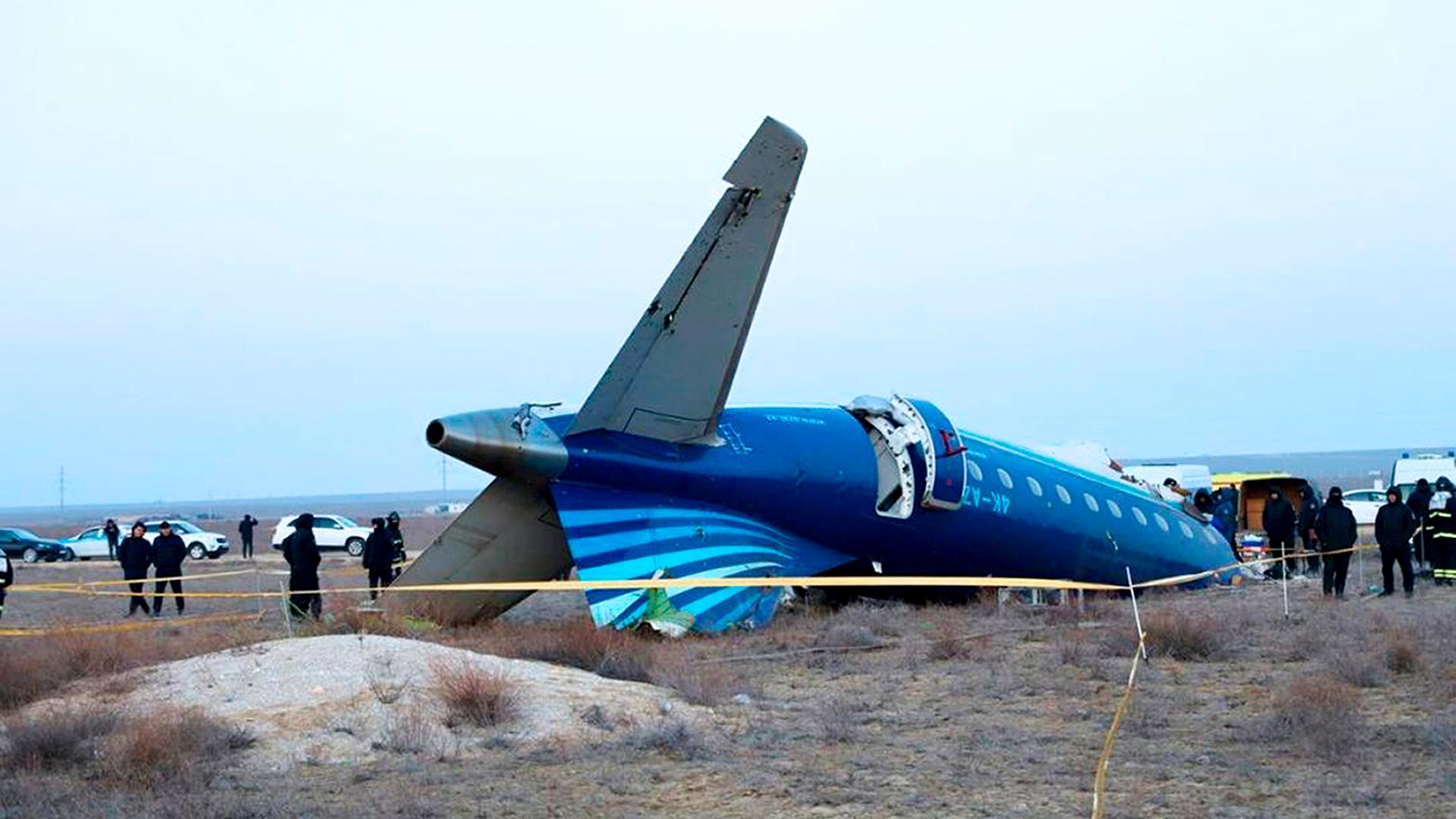 Das abgestürzte Flugzeug liegt auf dem Kopf. Mehrere Menschen stehen um die Maschine.