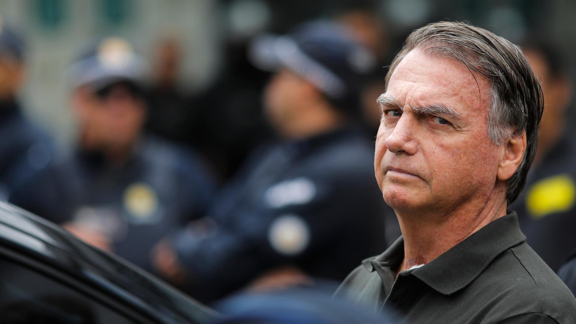 Jair Bolsonaro steht an einem Auto und schaut grimmig.
