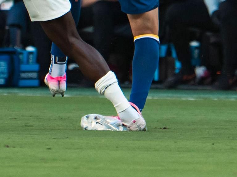 Beine von Fußballspielern während eines Zweikampfs, ein Spieler tritt dem anderen auf das Fußgelenk.