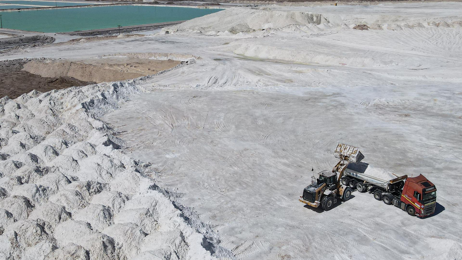 Arbeiter einer Lithiummine transportieren auf einem Lkw ein Nebenprodukt über den Salar de Atacama. Man sieht eine weiße Salzebene in der chilenischen Atacama-Wüste.