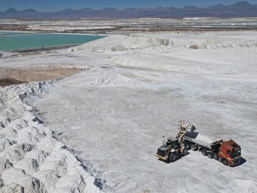 Arbeiter einer Lithiummine transportieren auf einem Lkw ein Nebenprodukt über den Salar de Atacama. Man sieht eine weiße Salzebene in der chilenischen Atacama-Wüste.