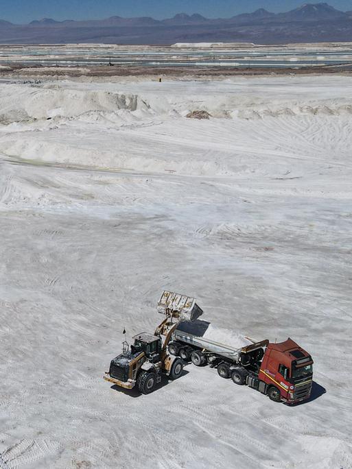 Arbeiter einer Lithiummine transportieren auf einem Lkw ein Nebenprodukt über den Salar de Atacama. Man sieht eine weiße Salzebene in der chilenischen Atacama-Wüste.