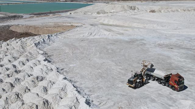 Arbeiter einer Lithiummine transportieren auf einem Lkw ein Nebenprodukt über den Salar de Atacama. Man sieht eine weiße Salzebene in der chilenischen Atacama-Wüste.