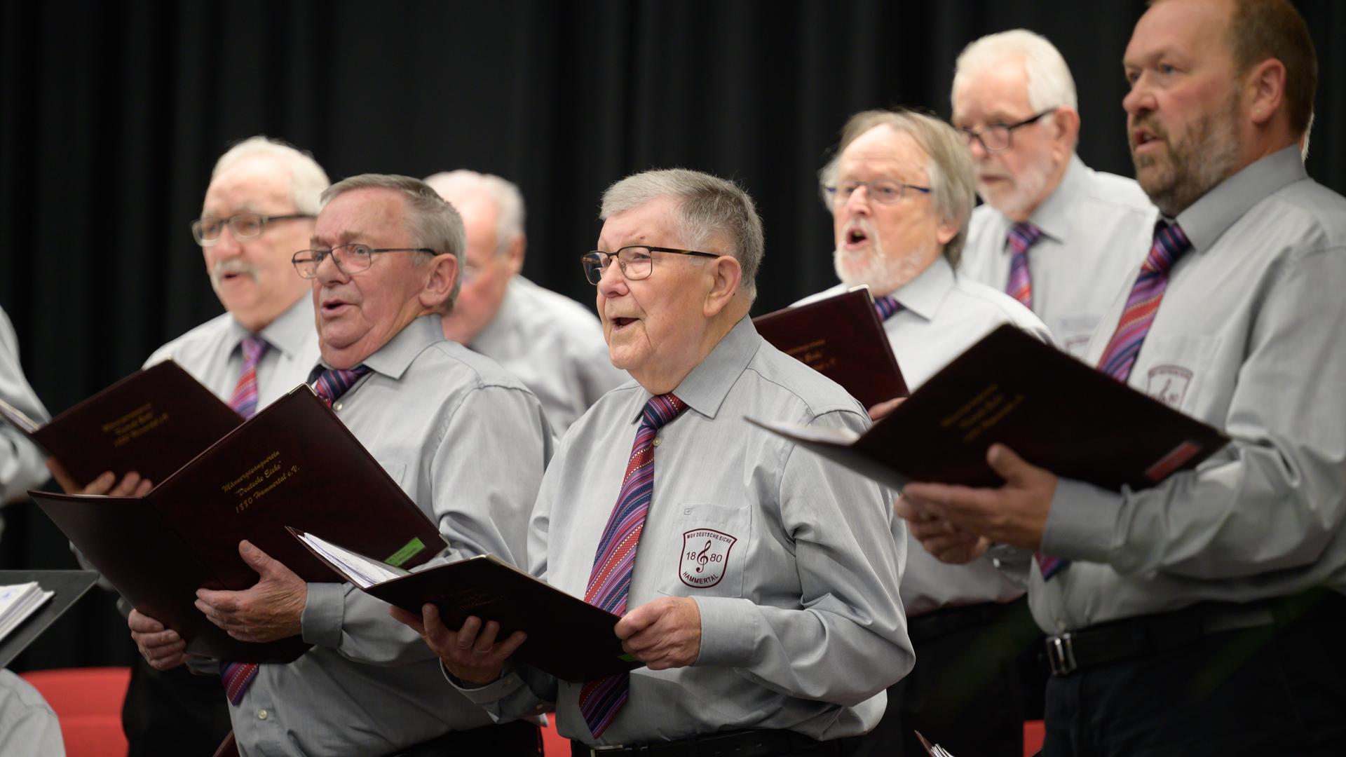 Sänger des Männergesangverein MGV Deutsche Eiche 1880 Hammertal stehen bei einem Konzert auf der Bühne und singen.