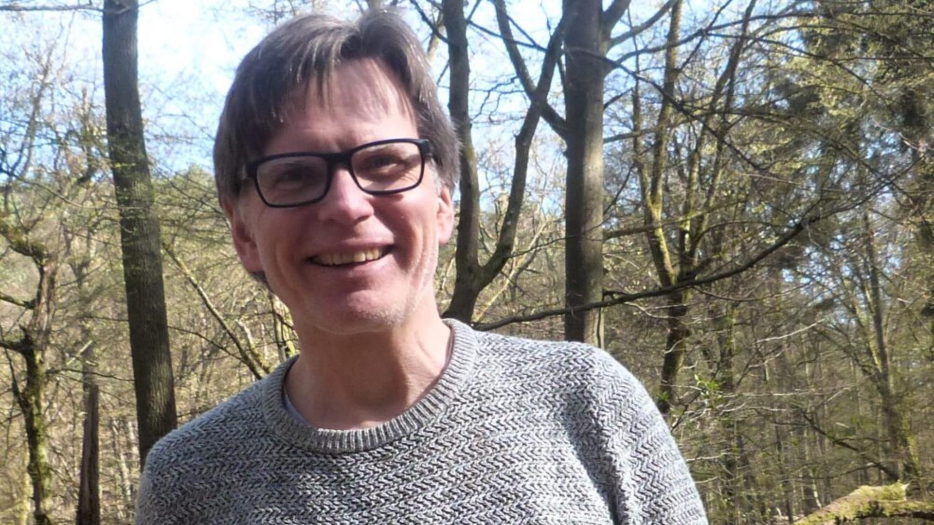 Ein Mann mit Brille lacht offen in die Kamera