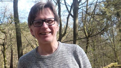 Ein Mann mit Brille lacht offen in die Kamera