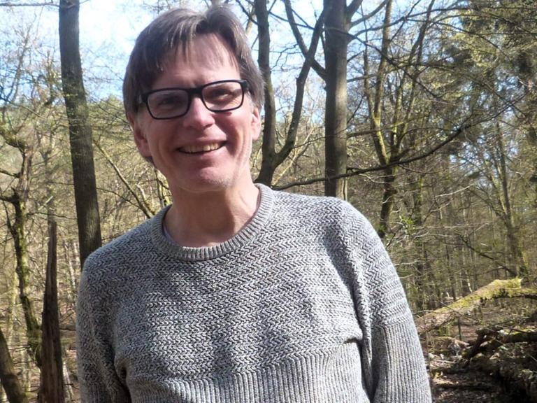 Ein Mann mit Brille lacht offen in die Kamera