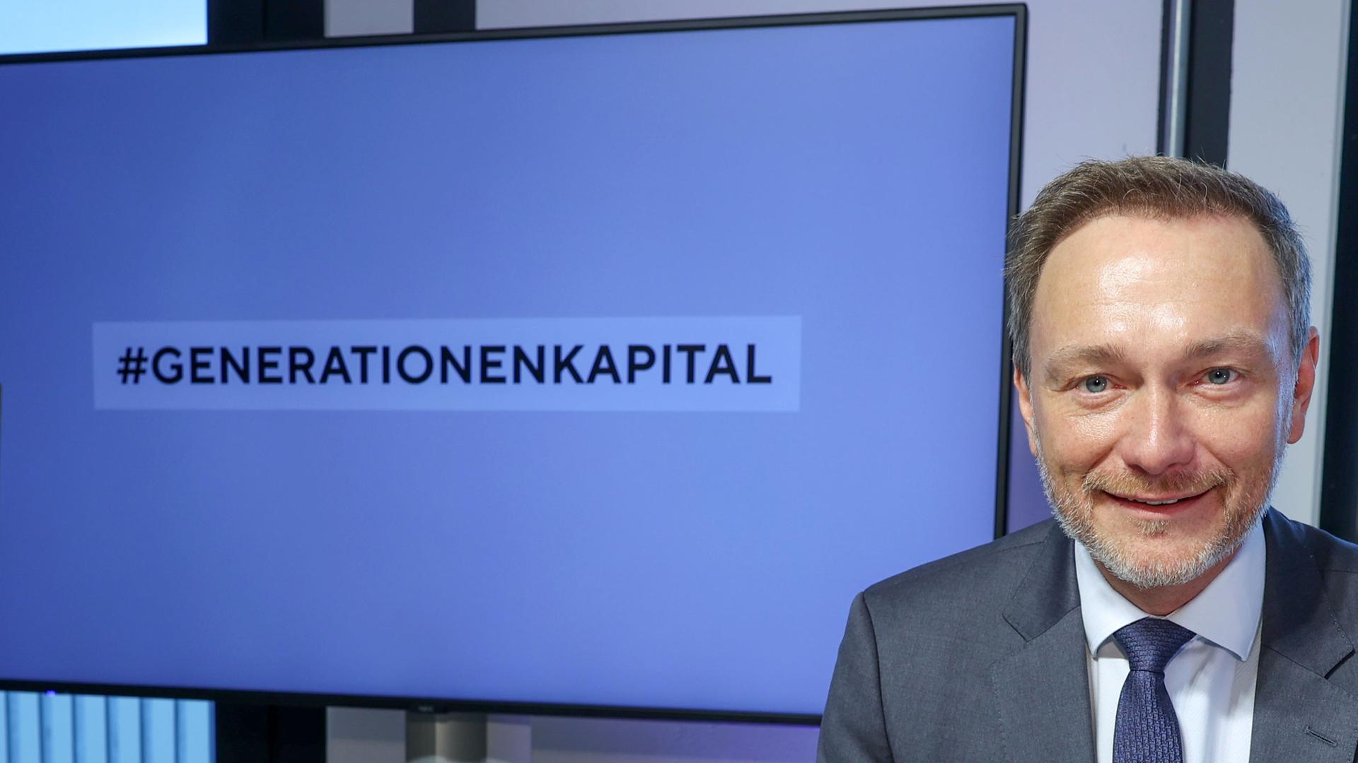 Ein Mann mit hellen Haaren schaut in die Kamera und lacht. Er trägt einen Anzug. Hinter ihm ist ein Monitor auf dem "Generationenkapital" steht. Ees ist Christian Lindner (FDP). Der Bundesfinanzminister nimmt an einer Veranstaltung in Frankfurt teil. Ein Mann mit hellen Haaren schaut in die Kamera und lacht. Er trägt einen Anzug. Hinter ihm ist ein Monitor auf dem "Generationenkapital" steht. Ees ist Christian Lindner (FDP). Der Bundesfinanzminister nimmt an einer Veranstaltung in Frankfurt teil.
