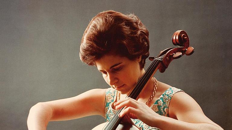Auf dem Bild ist eine Frau zu sehen, die Cello spielt. 