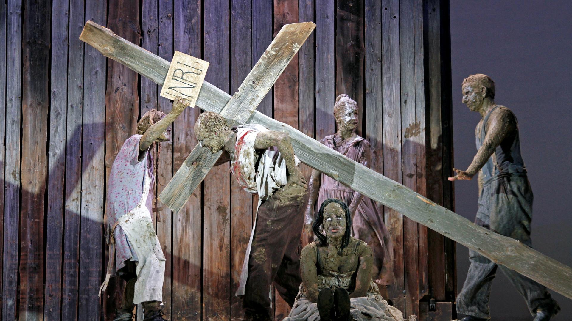 Schauspieler mit einem Kreuz auf einer Bühne.