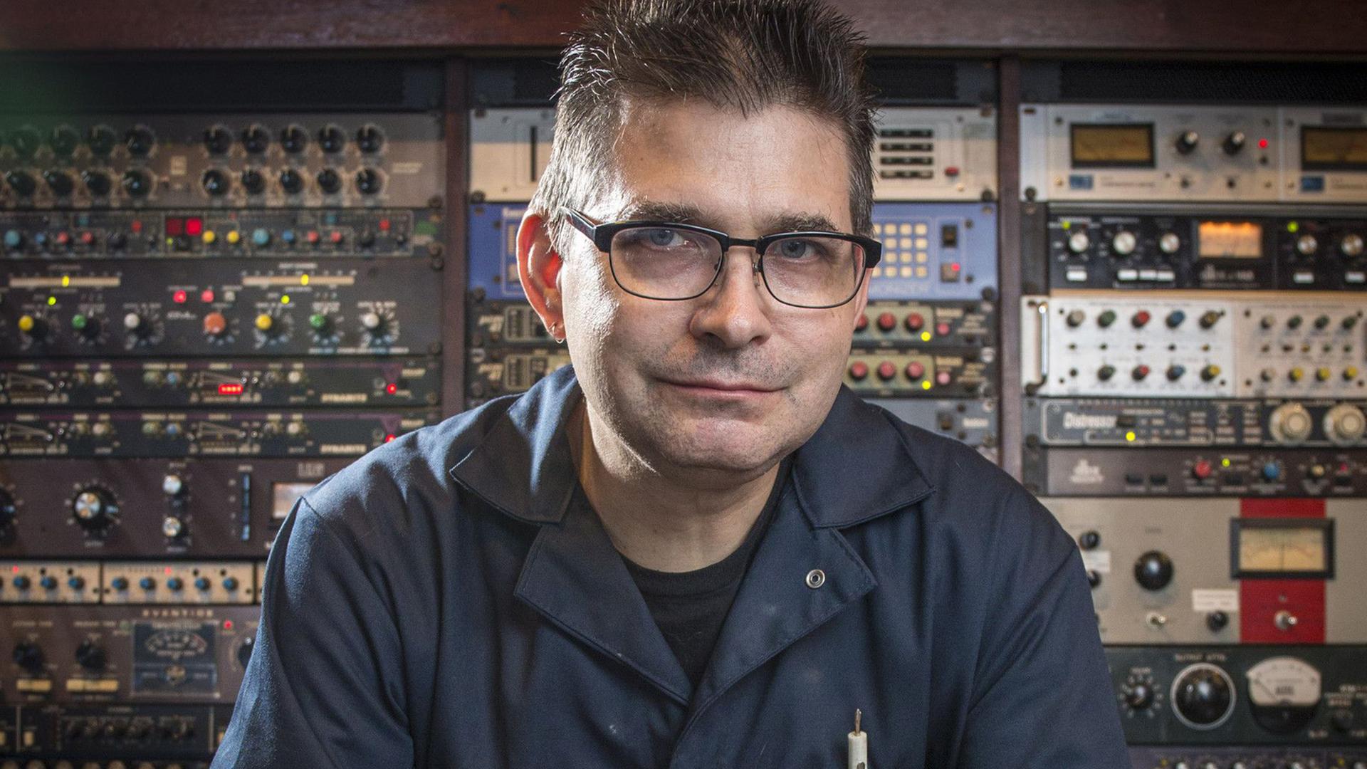 Steve Albini posiert im Jahr 2014 in seinem Studio vor einer Wand mit Technik-Equipment für ein Foto.