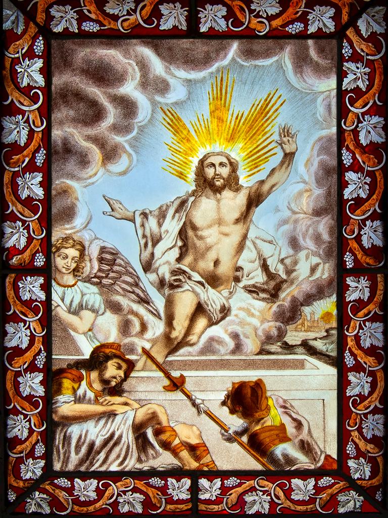 Auf einem Kirchenfenster ist Jesus zu sehen, der gerade von einem Engel begleitet durch Wolken in den Himmel fliegt.