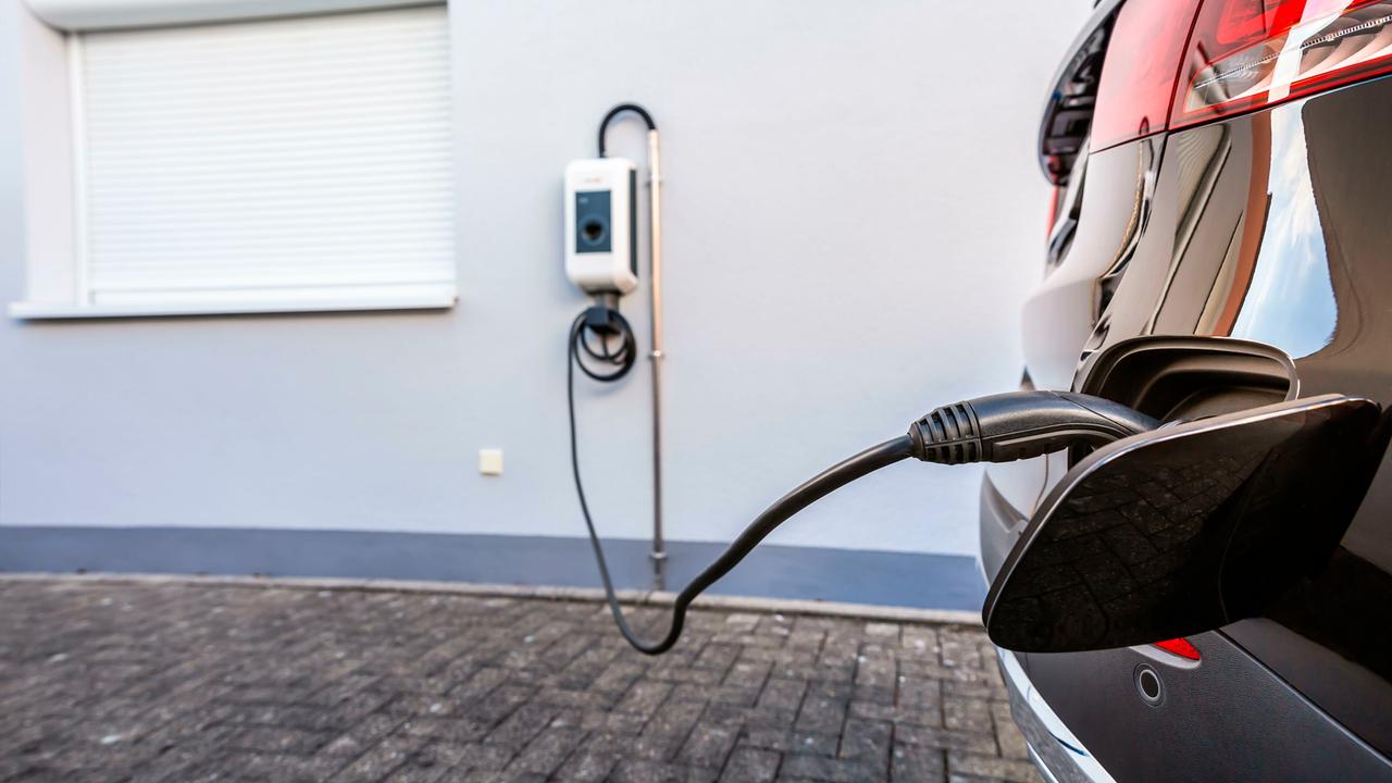 Ein E-Auto ist an eine Wallbox an einer Hauswand angeschlossen