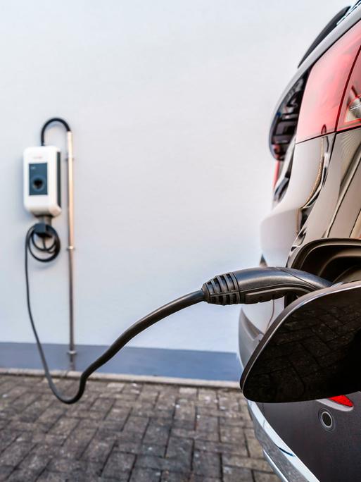 Ein E-Auto ist an eine Wallbox an einer Hauswand angeschlossen