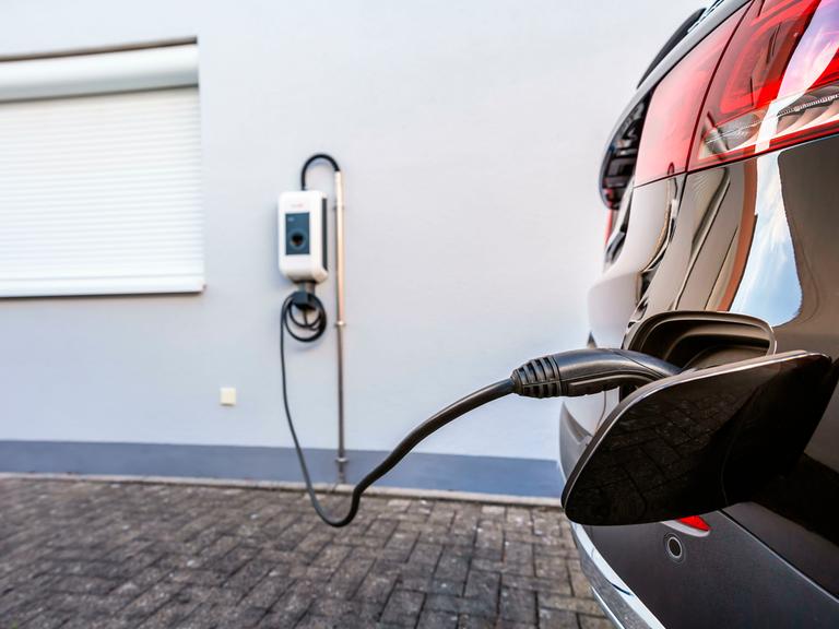 Ein E-Auto ist an eine Wallbox an einer Hauswand angeschlossen