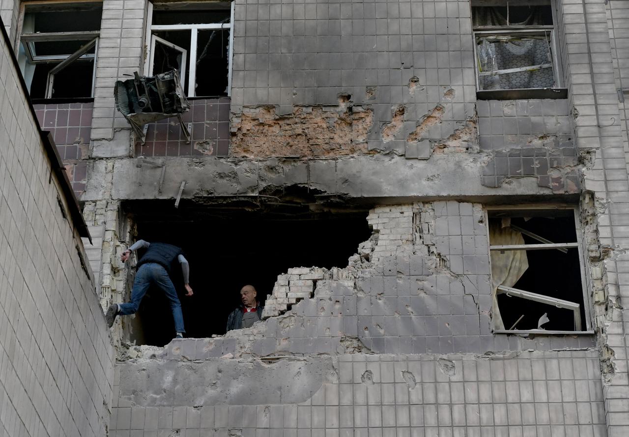 Bewohner untersuchen nach russischen Drohenangriffen ein teilweise zerstörtes Wohngebäude in Kiew.