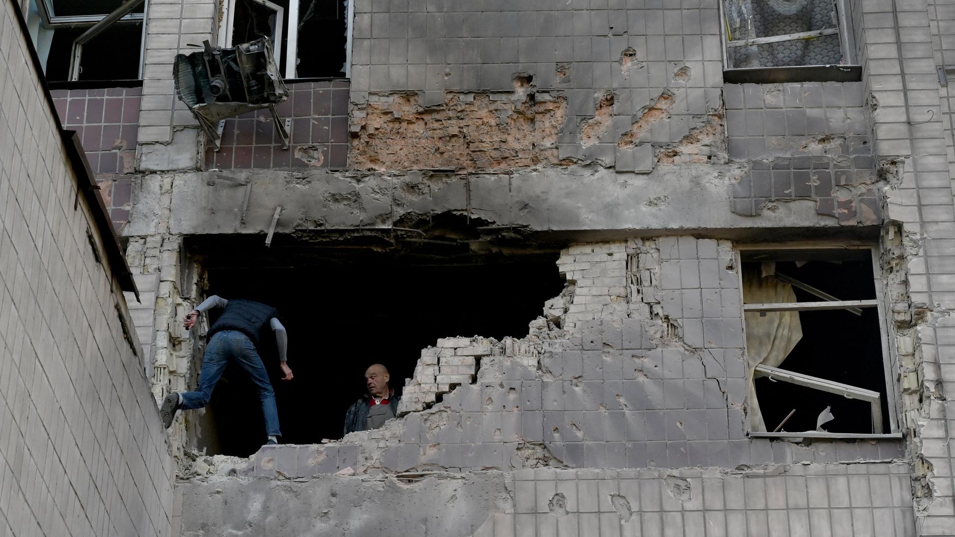 Bewohner untersuchen nach russischen Drohenangriffen ein teilweise zerstörtes Wohngebäude in Kiew.