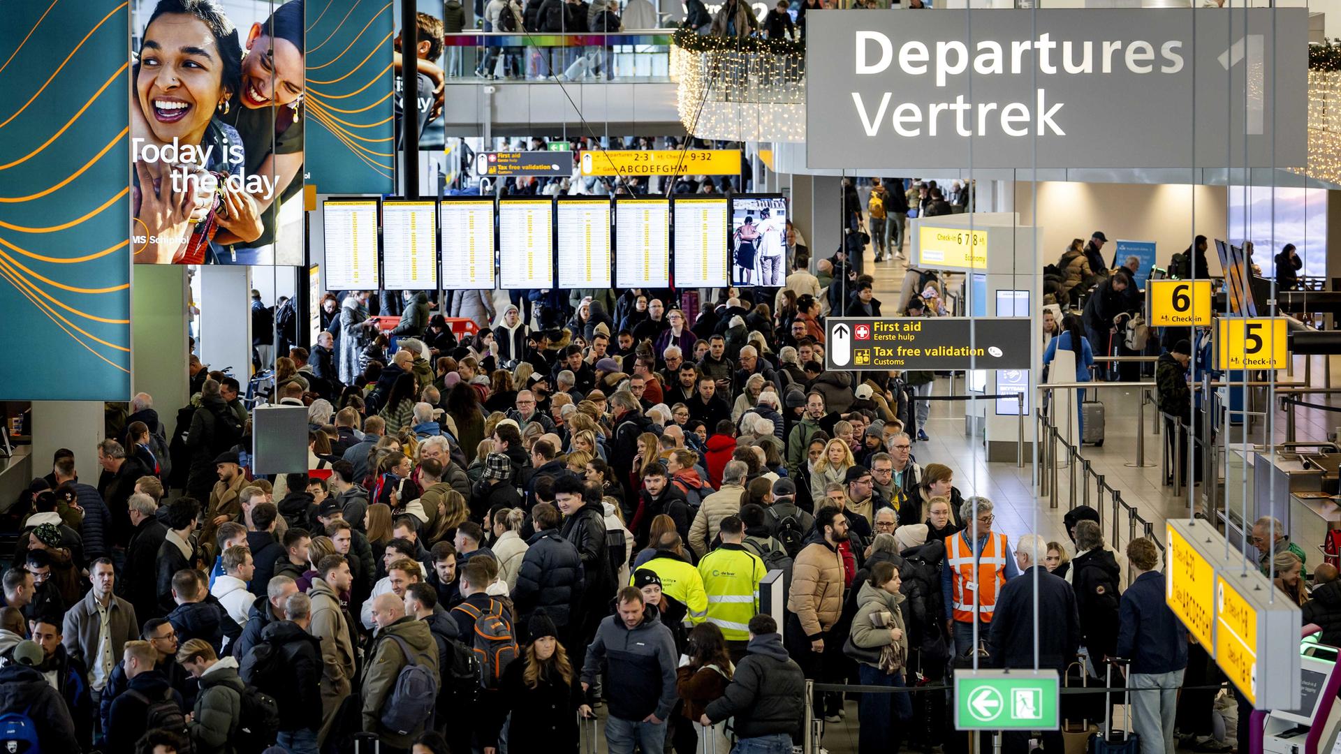 Ein Terminal am Flughafen Schiphol. Zahlreiche Reisende warten an den Schaltern.