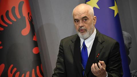 Edi Rama steht vor der albanischen und der europäischen Flagge und spricht.
