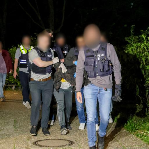Einsatzkräfte der Polizei führen einen Tatverdächtigen in Heiligenhaus ab. Gesichter der Personen sind auch rechtlichen gründen verpixelt