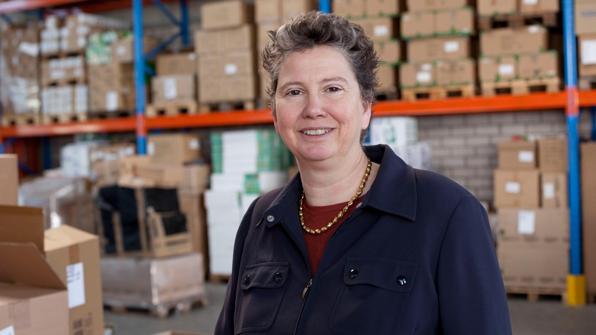 Die Sozialunternehmerin Juliane Kronen steht vor Regalen in ihrem Warenlager. 