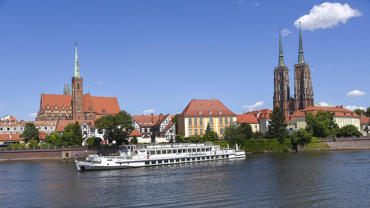Panorama der Stadt Breslau mit der St. John-Kathedrale im Hintergrund, im Vordergrund ein Schiff auf der Oder.