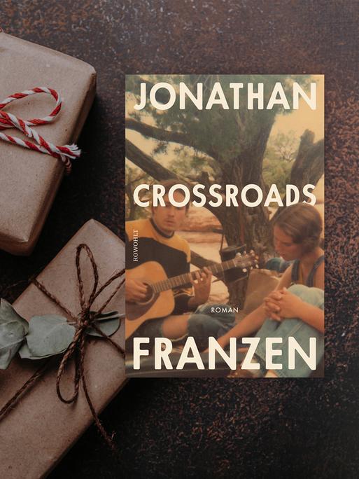 Buchcover zu "Crossroads" von Jonathan Franzen. Im Hintergrund braune Päckchen mit weiß-roten Schleifen.