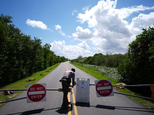 Ein Mann in Uniform öffnet kurzzeitig die Einfahrt in eine abgesperrte Straße. Ein Mann in Uniform öffnet kurzzeitig die Einfahrt in eine abgesperrte Straße.