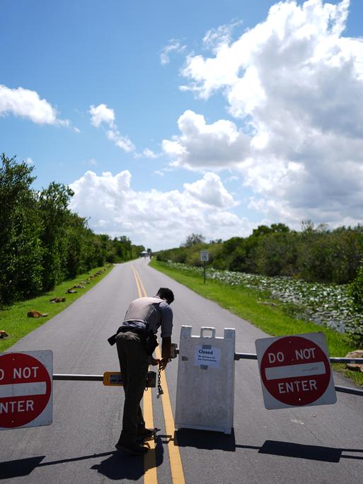 Ein Mann in Uniform öffnet kurzzeitig die Einfahrt in eine abgesperrte Straße. Ein Mann in Uniform öffnet kurzzeitig die Einfahrt in eine abgesperrte Straße.