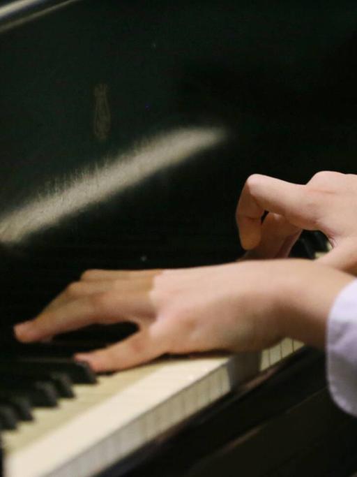Zwei junge Hände spielen Chopin auf einerm Flügel.