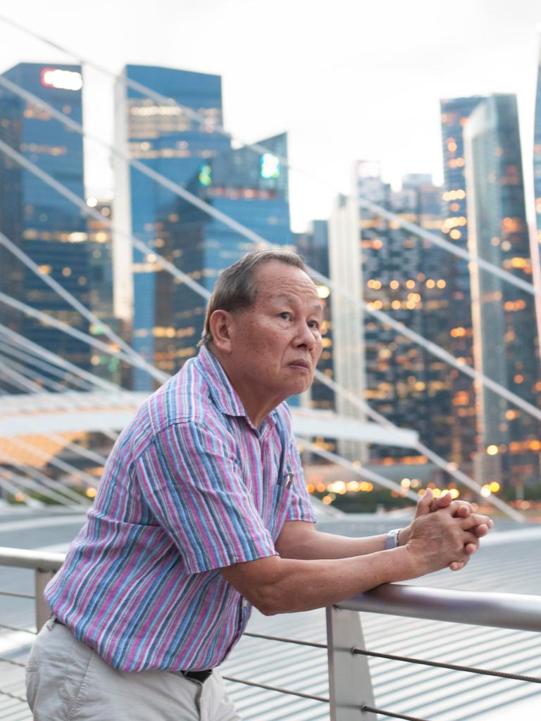 Singapur – Asiatisches Porträt: Ein älterer Mann blickt auf die modern Hochhauslandschaft in Singapur und denkt über die Zukunft nach