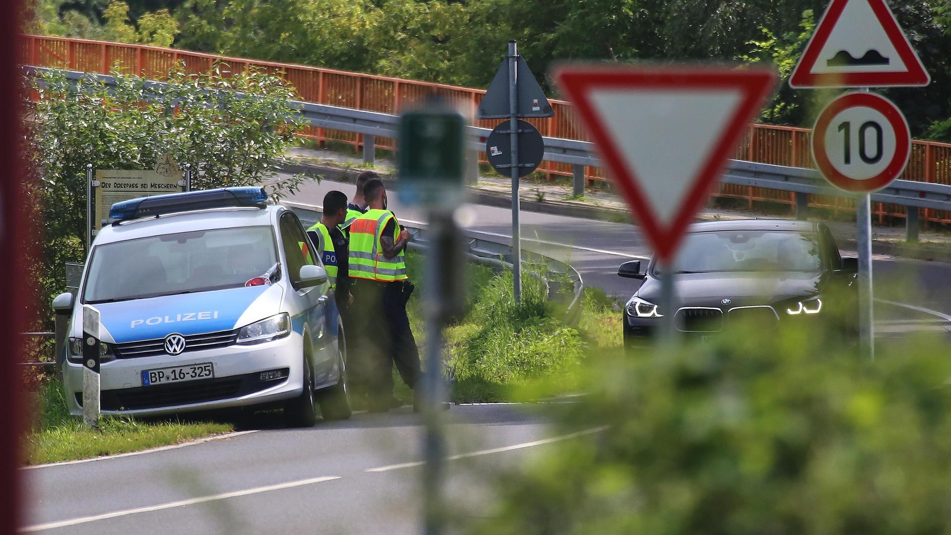 Deutsche Polizisten stehen an der West-Oder-Brücke in Mescherin, Brandenburg, und kontrollieren aus Polen kommende Pkw.